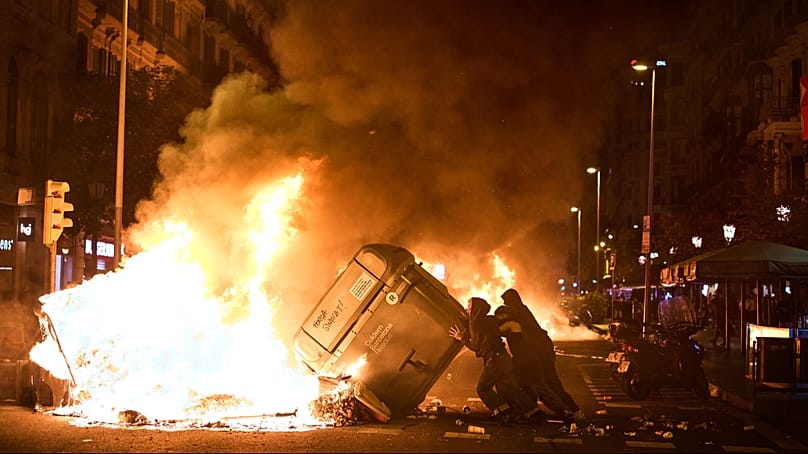 Os manifestantes incendiaram contentores do lixo durante confrontos com a polícia em Barcelona, Espanha, na segunda-feira, 5 de outubro de 2026. 