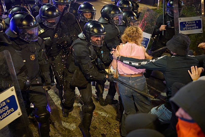 Agentes da polícia de intervenção utilizam bastões para dispersar manifestantes após um protesto contra a crise da habitação em Espanha, em Barcelona, a 5 de outubro.