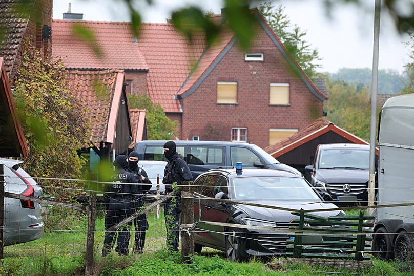 Police officers stand at the entrance of former intelligence chief August Hanning's home, who was arrested on suspicion of espionage, in Nordwalde, Tuesday, Oct. 6, 2026