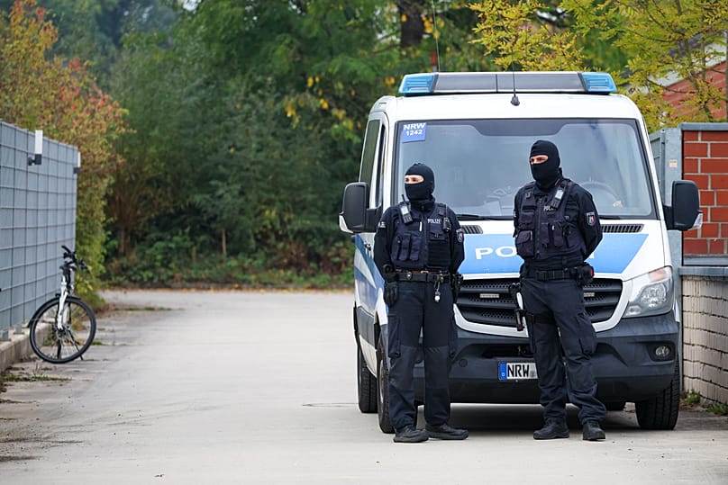 Police officers stand at the entrance of former intelligence chief August Hanning's home, who was arrested on suspicion of espionage, in Nordwalde, Tuesday, Oct. 6, 2026