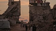 فلسطينيون يسيرون في شارع تحيط به مبانٍ دمرتها غارات إسرائيلية في غزة، الثلاثاء 6 أكتوبر/تشرين الأول 2026. 