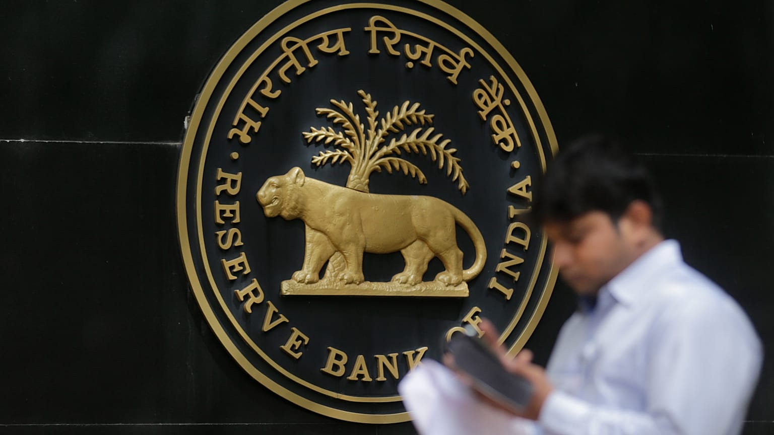 صورة أرشيفية: صحفي يتفقد هاتفه المحمول خارج بنك الاحتياط الهندي (RBI) في مومباي، سبعة يونيو 2017