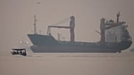 A motorboat passes an anchored cargo ship in the Strait of Hormuz off Bandar Abbas, Iran, early Monday, Sept. 28, 2026.