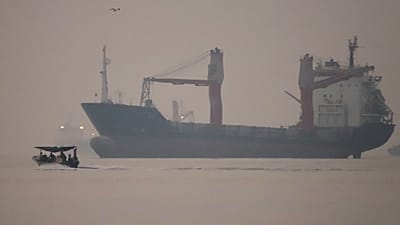 Una lancha motora pasa junto a un carguero fondeado en el estrecho de Ormuz, frente a Bandar Abbas, Irán, en la madrugada del lunes 28 de septiembre de 2026.
