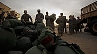 جنود أميركيون من الفرقة الأولى للفرسان يحملون أمتعتهم استعدادًا للعودة من العراق عبر معسكر في الكويت، في 15 ديسمبر/كانون الأول 2011.