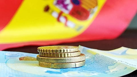 A couple of coins and a banknote against the backdrop of the Spanish flag