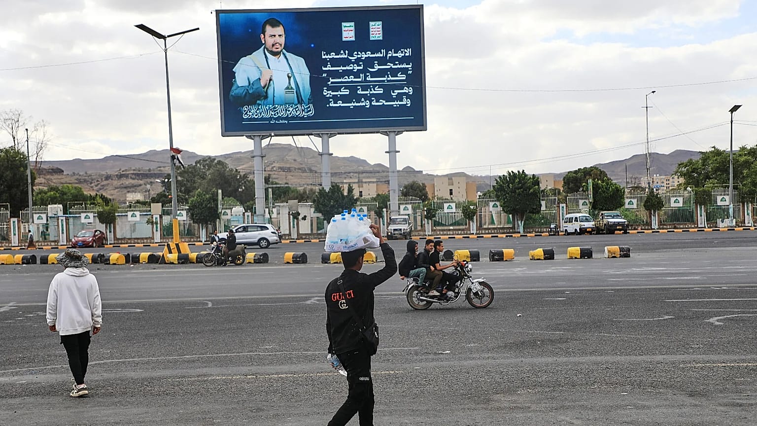 Yemen'in başkenti Sana'da bir satıcı, üzerinde Husi lideri Abdulmelik el-Husi'nin yer aldığı bir reklam panosunun altından geçiyor, 5 Ekim 2026.