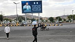 Yemen'in başkenti Sana'da bir satıcı, üzerinde Husi lideri Abdulmelik el-Husi'nin yer aldığı bir reklam panosunun altından geçiyor, 5 Ekim 2026.