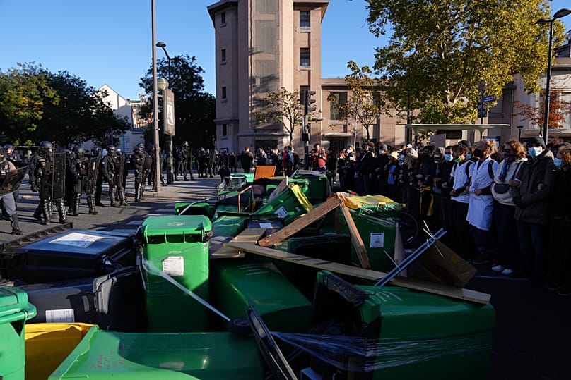 Des élèves, des personnels enseignants et des policiers devant une barricade de poubelles devant le lycée Hélène Boucher à Paris