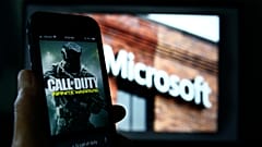 An image from Activision's Call of Duty is shown on a smartphone near a photograph of the Microsoft logo.