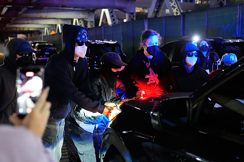 People block a car from driving near the scene of a shooting Thursday, Oct. 8, 2026, in New York