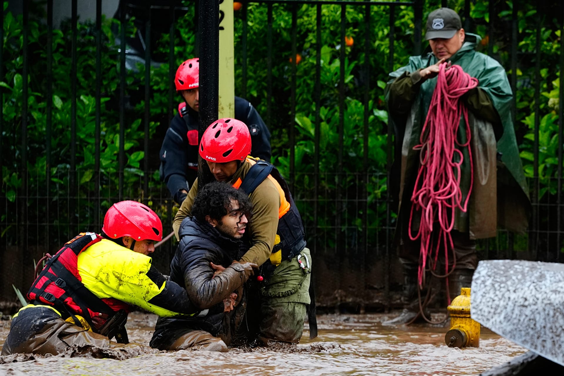 A man is pulled to safety by rescue workers after heavy rains caused flash flooding in the Las Condes district of Santiago, Chile, Thursday, Oct. 8, 2026