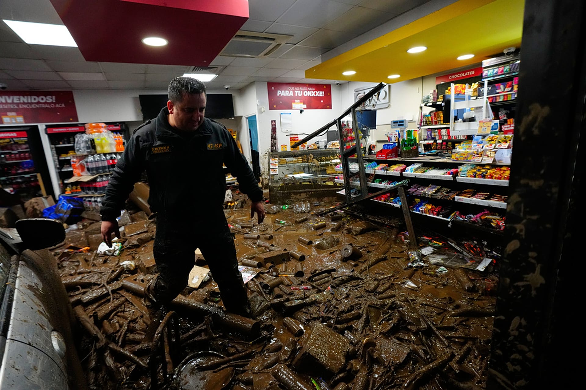 A rescue worker walks through muddy debris in a shop damaged by flash flooding caused by heavy rains in the Las Condes district of Santiago, Chile, Thursday, Oc