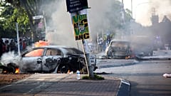 A car burns near a political party poster after it was set alight during protests related to immigration issues in Soweto.