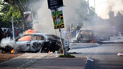 Une voiture brûle près d'une affiche d'un parti politique, après avoir été incendiée lors de manifestations liées à l'immigration à Soweto.