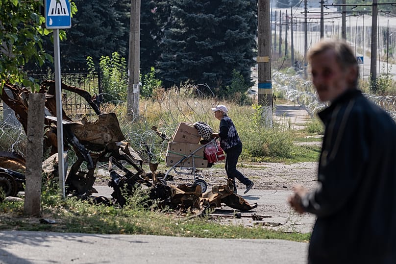 Местная жительница везет на тележке свои вещи по улицам Дружковки в Донецкой области Украины, 12 сентября 2026 года.