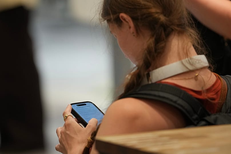 Egy tinédzser a mobiltelefonját nézi Londonban, 2026. június 15-én.