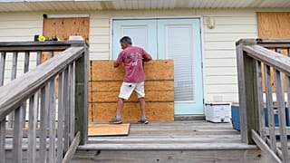 Larry Smith protege su casa con tableros de madera contrachapada ante la llegada prevista del huracán Isaias a la costa del Golfo, en Dauphin Island (Alabama)