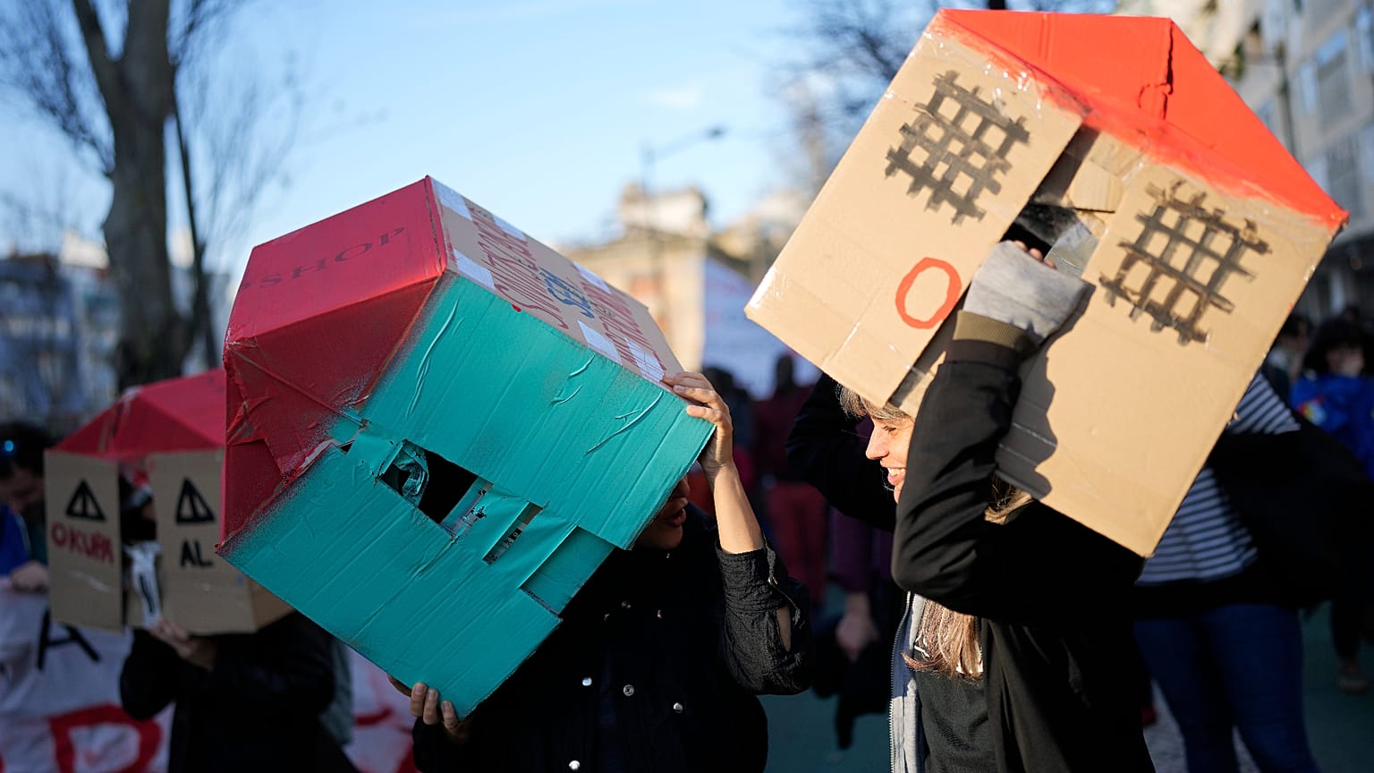 ARQUIVO (27.01.2024): Duas jovens usam casas de cartão na cabeça durante uma manifestação de protesto contra a crise da habitação em Portugal