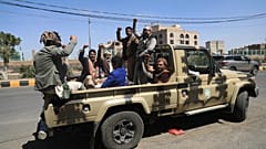 أنصار الحوثيين يرددون شعارات أثناء ركوبهم في الجزء الخلفي من شاحنة صغيرة في تجمع قبلي مسلح في صنعاء باليمن