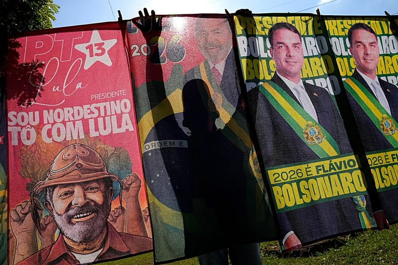 Um vendedor ambulante organiza bandeiras de campanha dos candidatos Luiz Inácio Lula da Silva e Flávio Bolsonaro para venda