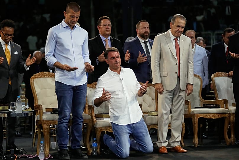 O candidato presidencial da oposição, o senador Flavio Bolsonaro, ajoelha-se enquanto ouve um pregador durante Ministério das Assembleias de Deus da Igreja Pentecostal 