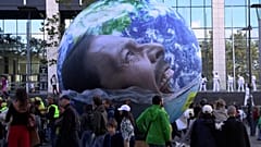 A giant inflatable globe depicting a screaming man is carried through the demonstration.