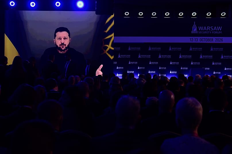 People watch Ukrainian President Volodymyr Zelenskyy on a large screen as he speaks at the Warsaw Security Forum in Warsaw, 12 October, 2026
