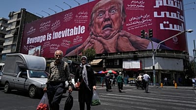 Transeúntes pasan ante un cartel en Teherán donde se ve al presidente de EE UU Donald Trump sujetado del cuello junto al lema «La venganza es inevitable» en inglés y farsí.