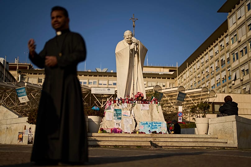 People stand next to the statue of Pope John Paul II outside the Agostino Gemelli hospital in Rome, 6 March, 2025
