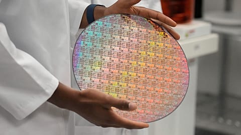 Yann Lapnet, holds a silicon wafer with chips etched into at Applied Materials as Vice President Kamala Harris tours a site where Applied Materials plans to build a $4 billion