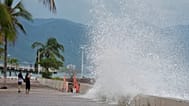 Unos turistas toman fotos del agua que rompe contra el muro mientras el huracán Simon se acerca a Puerto Vallarta, México, el 11 de octubre de 2026.