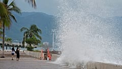 Unos turistas toman fotos del agua que rompe contra el muro mientras el huracán Simon se acerca a Puerto Vallarta, México, el 11 de octubre de 2026.