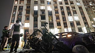 Une voiture et une moto brûlées se trouvent devant un immeuble résidentiel de plusieurs étages endommagé par une frappe de drone russe à Kyiv, en Ukraine, lundi 12 octobre 2026.