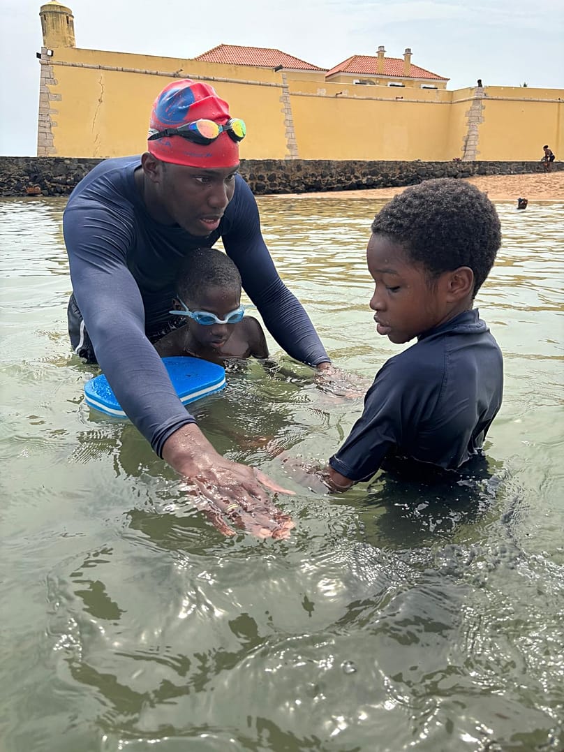José ensina uma criança na praia PM, em São Tomé