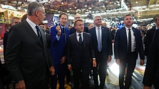French President Emmanuel Macron, centre, flanked by Stellantis chairman John Elkann, centre left, visits the Paris Motor Show
