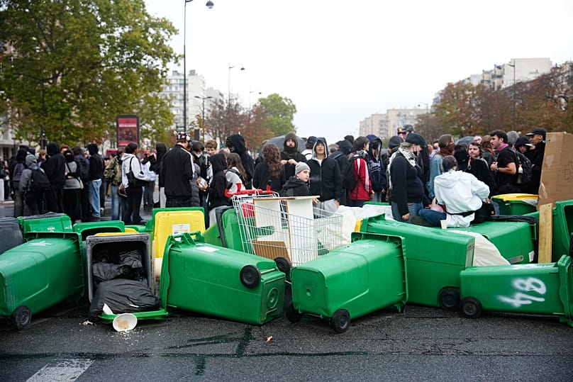Students stand in front of a high school blockaded with garbage bins as they protest against under-resourced schools in Paris, 13 October, 2026