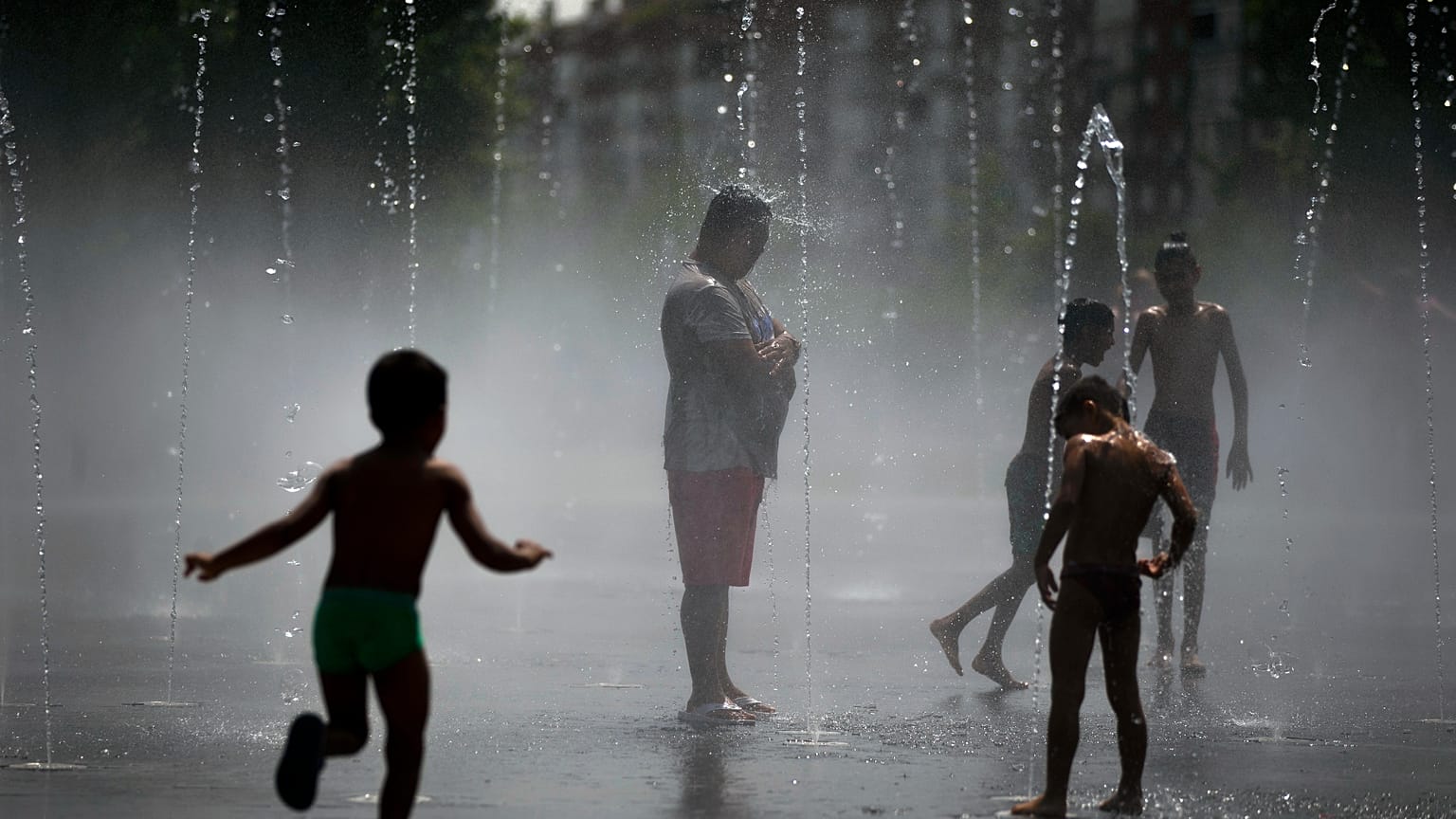 En una foto de archivo, unas personas se refrescan en una playa urbana del parque Madrid Río, en Madrid, el viernes 3 de agosto de 2018