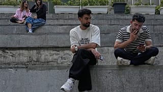 يقضي الشباب فترة ما بعد الظهر جالسين على الدرجات خارج مركز للتسوق في شمال طهران، إيران، الخميس 13 أغسطس 2026.
