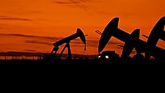 Um camião passa por bombas de extração de petróleo ao anoitecer perto de Karnes City, no Texas, em 1 de novembro de 2023