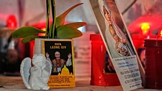 An image of Pope Leo XIV rests at the base of a statue of the late Pope John Paul II outside the Agostino Gemelli Polyclinic in Rome, 13 October, 2026