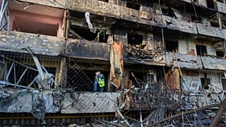 Сотрудник муниципальной службы осматривает поврежденный жилой дом после ночного ракетного обстрела Киева (Украина) со стороны России в среду, 14 октября 2026 года.