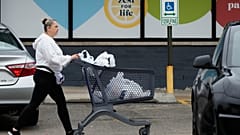 Arquivo - Uma mulher empurra um carrinho de compras ao sair de um supermercado em Arlington Heights, Illinois, quarta-feira, 30 de setembro de 2026.