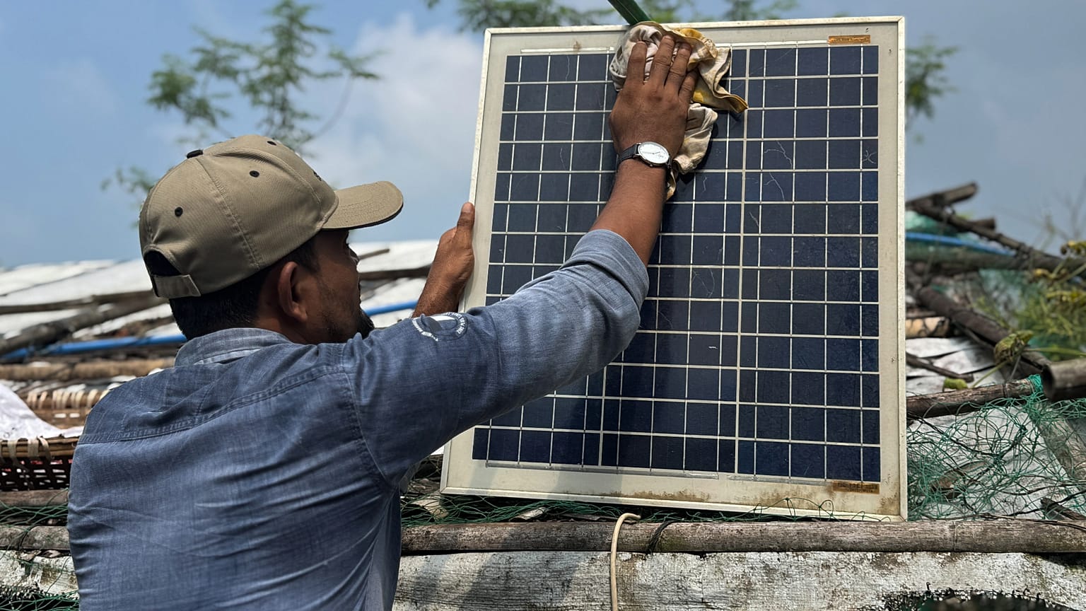 Auf diesem mit einem Handy aufgenommenen Foto reinigt Mohammed Saber am vierten Oktober 2026 in Teknaf, Bangladesch, ein Solarpanel, damit es richtig lädt.