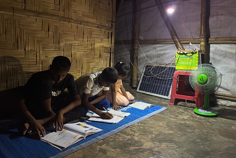 Auf dieser mit einem Handy aufgenommenen Aufnahme nutzen Kinder eine von einem Solarpanel gespeiste Lampe, um nachts in ihrer Unterkunft zu lernen, am dritten Oktober 2026 in Teknaf, Bangladesch. 