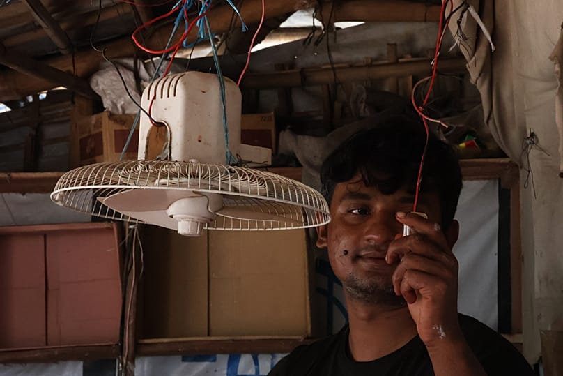 Auf dieser mit einem Handy aufgenommenen Aufnahme schaltet Mohammed Hares einen solarbetriebenen Ventilator in seinem Laden ein, am vierten Oktober 2026 in Teknaf, Bangladesch. 