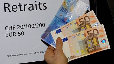 A woman holds 100 euro (pink banknotes at bottom) and 100 Swiss francs (blue banknote at top) she withdrew from an ATM in a bank in Geneva, Switzerland, on Tuesday, Jan. 8, 20