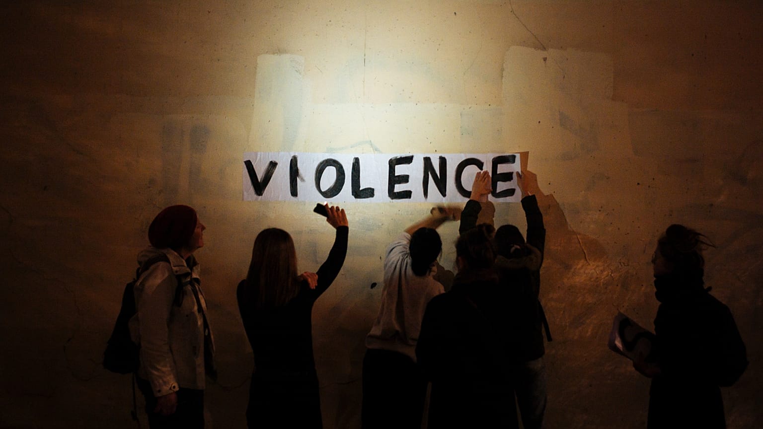 Le mot « violence » est collé sur un mur par un groupe de femmes dans une rue sombre de Paris. 