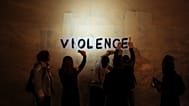 Le mot « violence » est collé sur un mur par un groupe de femmes dans une rue sombre de Paris. 