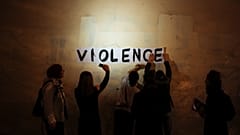 The word "violence" is pasted on a wall by a group of women in a dark Paris street.